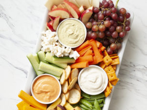 Charcuterie board with assortment of hummus, dips, vegetables, cheese and crackers beauty image